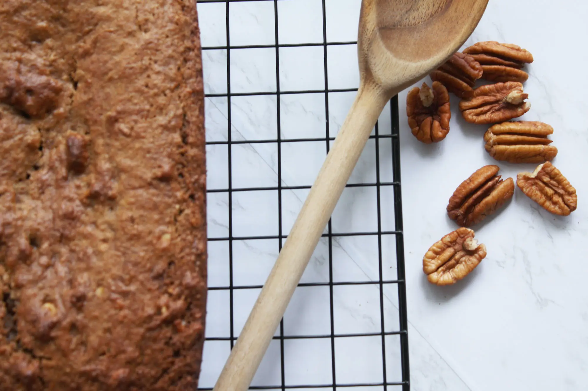 cinnamon pecan banana bread loaf overhead shot with wooden spoon and a handful of pecans | hearth health happiness