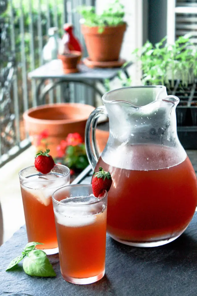 pitcher of strawberry basil iced tea with two additional glasses on outdoor table | food blog | summertime drinks | hearth health happiness