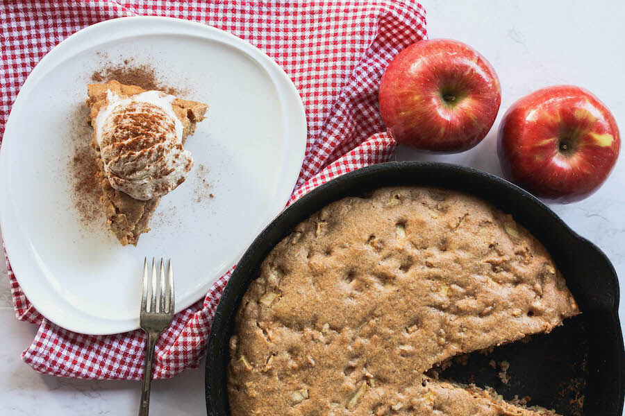overhead image of apple cinnamon skillet cake with slice next to skillet