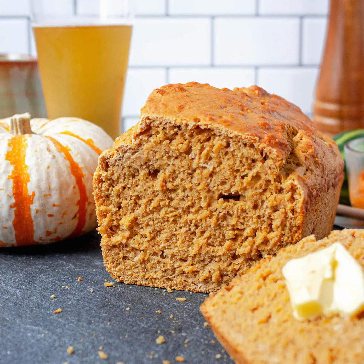 pumpkin beer bread on counter with slice in foreground
