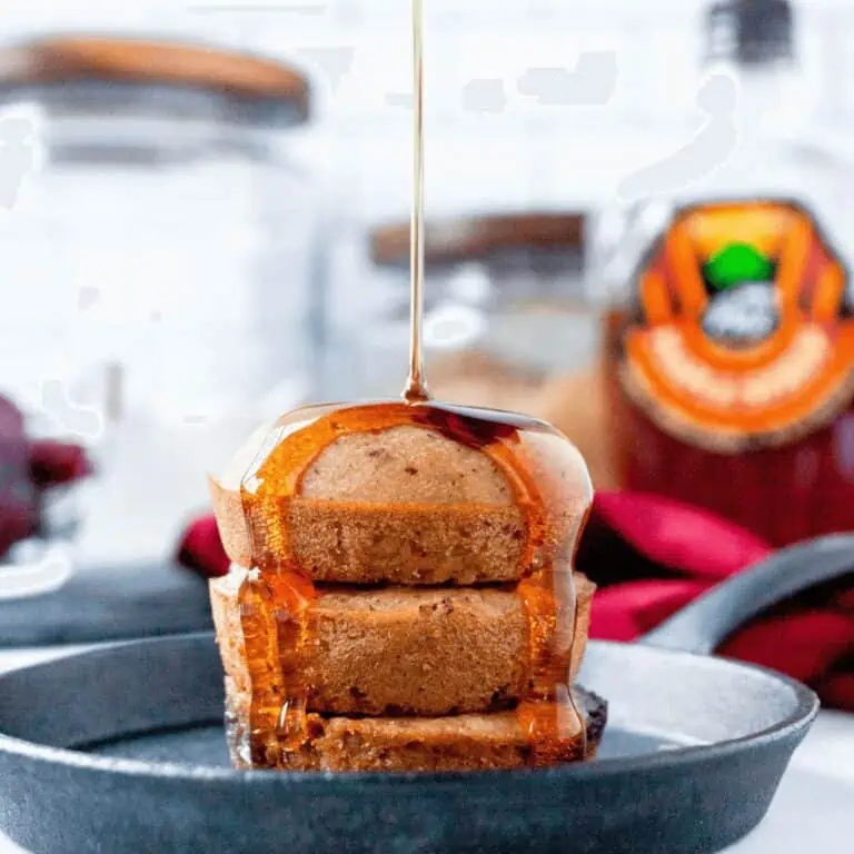 cherry mini pancakes stacked on small griddle with syrup pouring on top