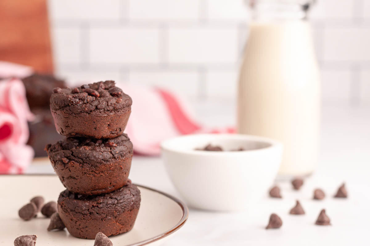 stacked chickpea brownie bites on plate with plant-based milk in background