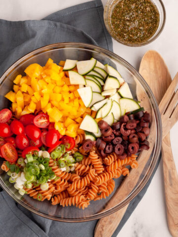 overhead image of red lentil pasta salad ingredients in serving bowl