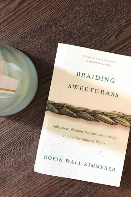 overhead image of braiding sweetgrass book on coffee table with candle