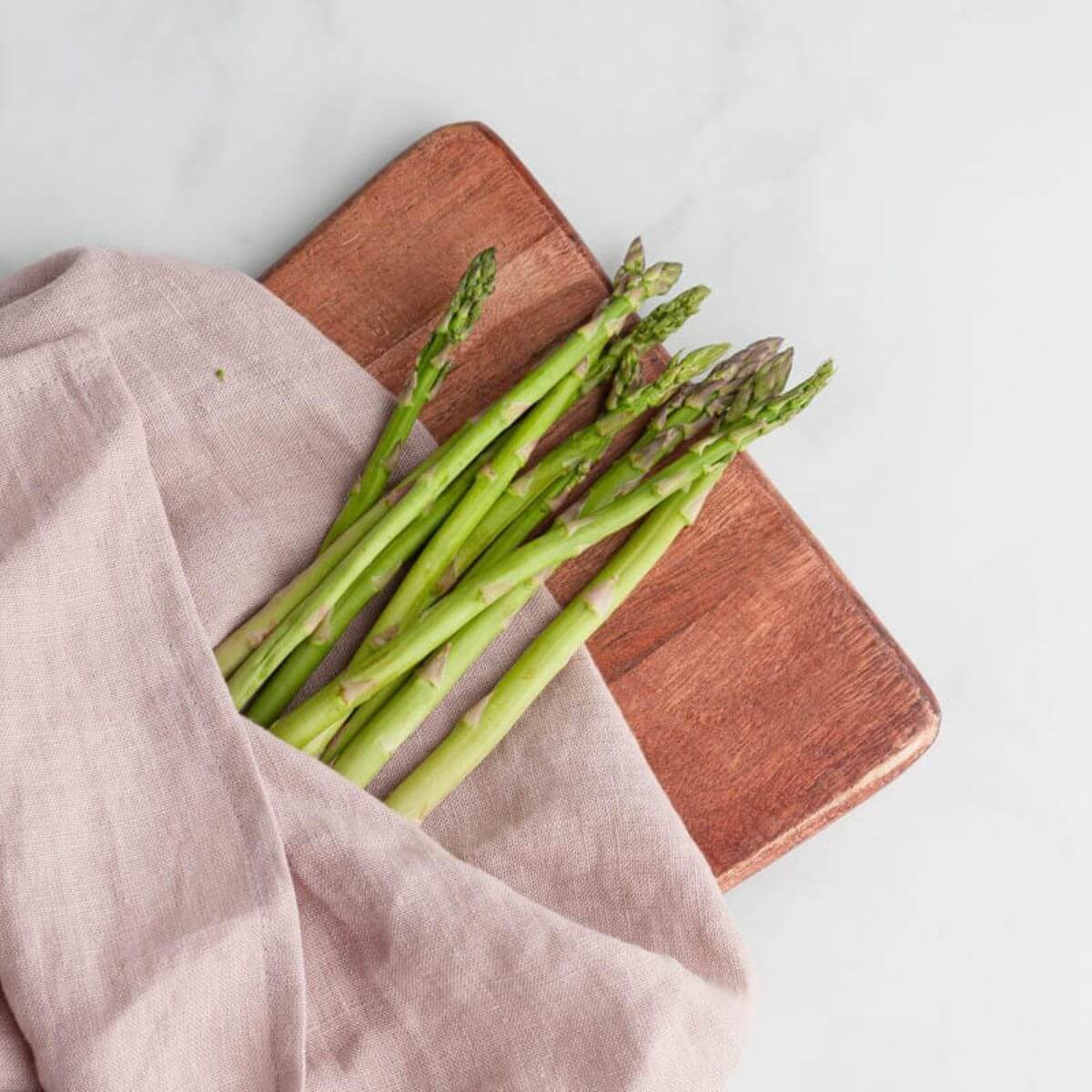 asparagus folded in rose colored tea towel on counter