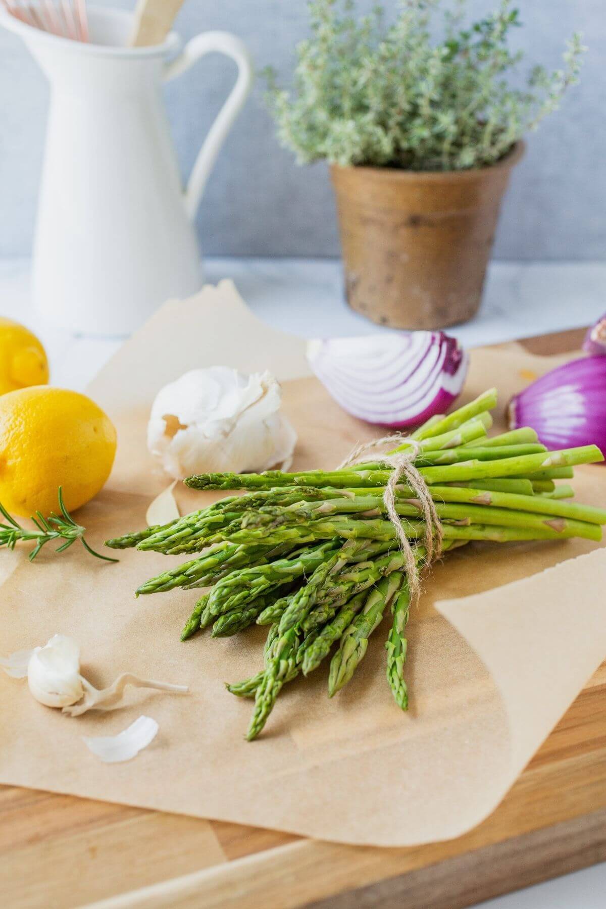 asparagus bundle on board with onion and lemon surrounding it