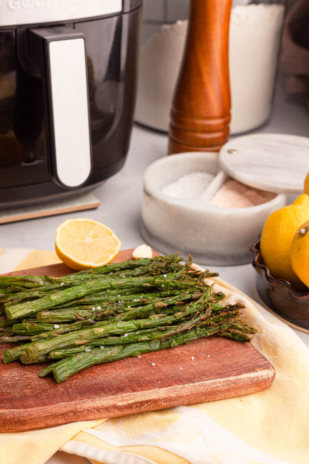side image of cooked air fryer asparagus on counter with air fryer in background
