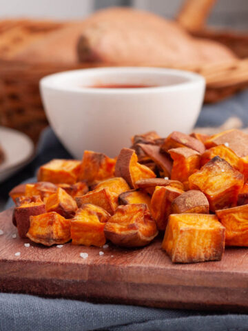 air fryer sweet potato cubes on board with ketchup in background