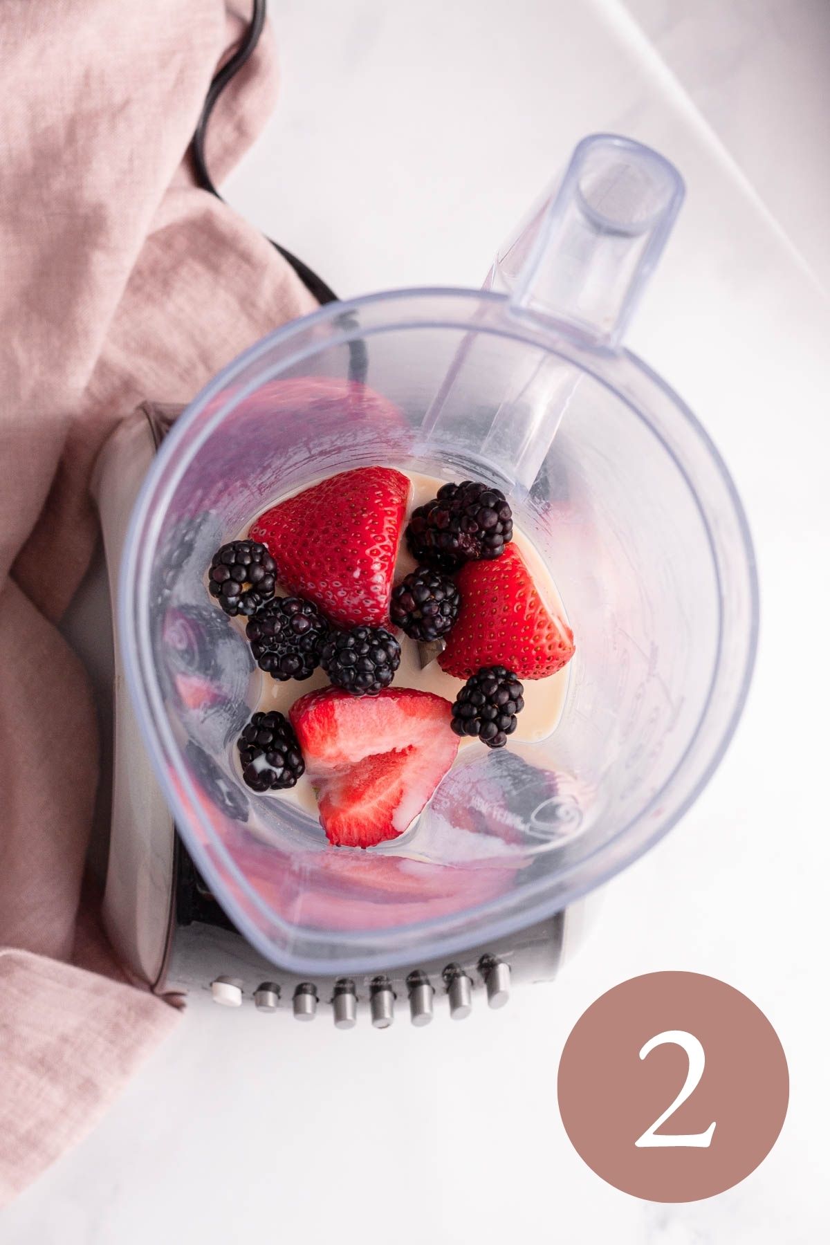 overhead image of strawberries blackberries and milk in blender