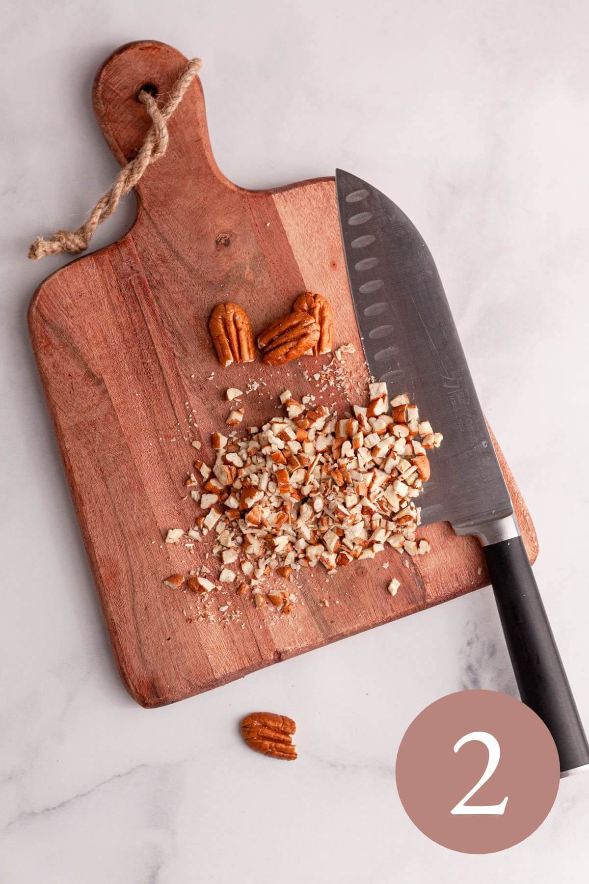 overhead image of chopped pecans on board with knife