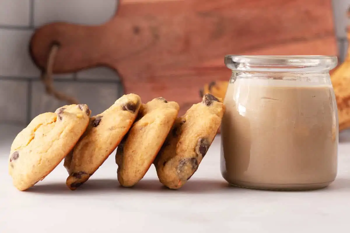 Banana tahini cookies propped on each other with jar of tahini to the right