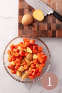 overhead image of chopped potatoes and carrots in bowl next to cutting board