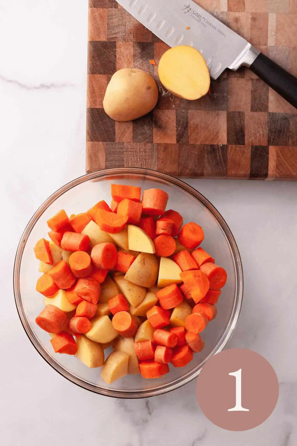Overhead image of chopped potatoes and carrots in clear bowl and cutting board