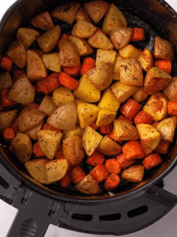overhead image of carrots and potatoes in air fryer basket