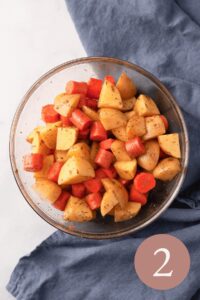 overhead image of chopped potatoes and carrots in bowl with added seasonings