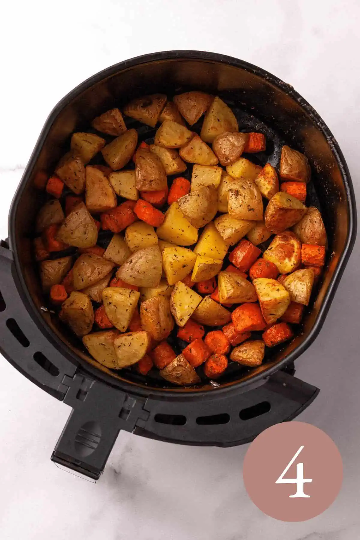 Overhead image of chopped potatoes and carrots in air fryer basket before frying