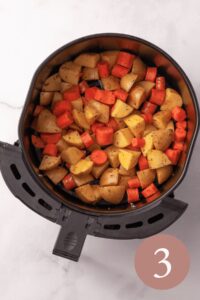overhead image of seasoned potatoes and carrots in air fryer basket