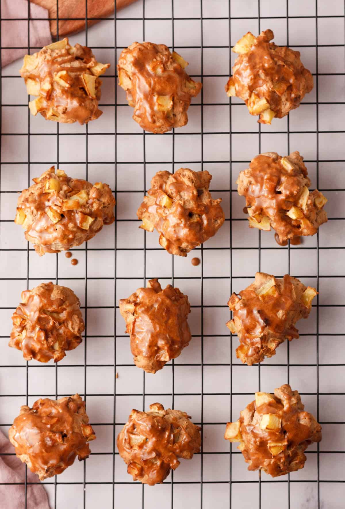 overhead image of applesauce fritters on cooling rack after they are topped with glaze