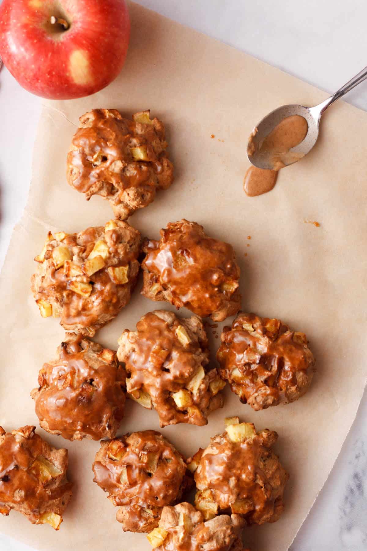 overhead image of applesauce fritters with glaze on parchment