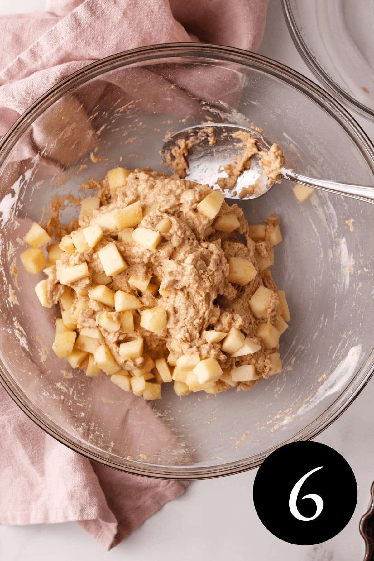 overhead image of fritter dough in bowl with apple bits sprinkled over the top