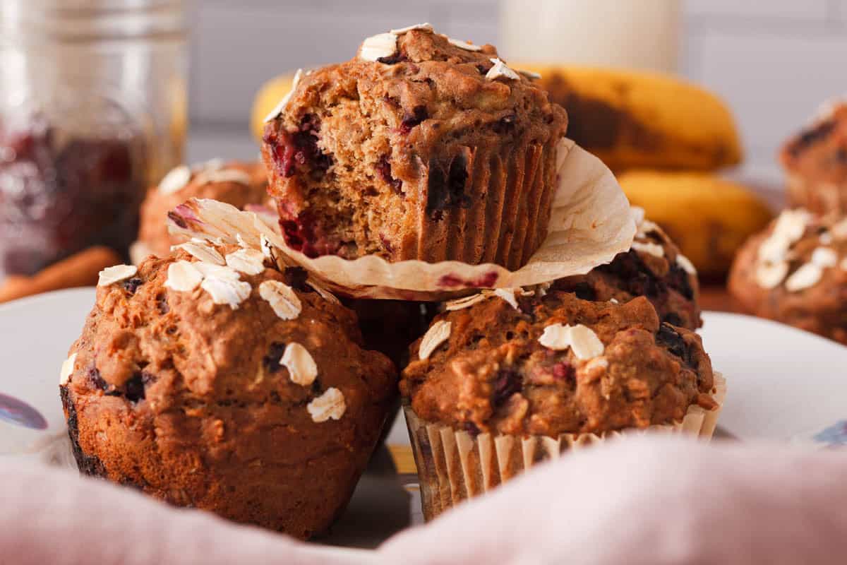 side image of banana blackberry muffins stacked and a bite taken out of the top muffin
