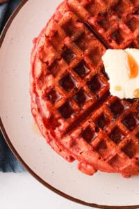 overhead image of waffle on plate with butter and syrup