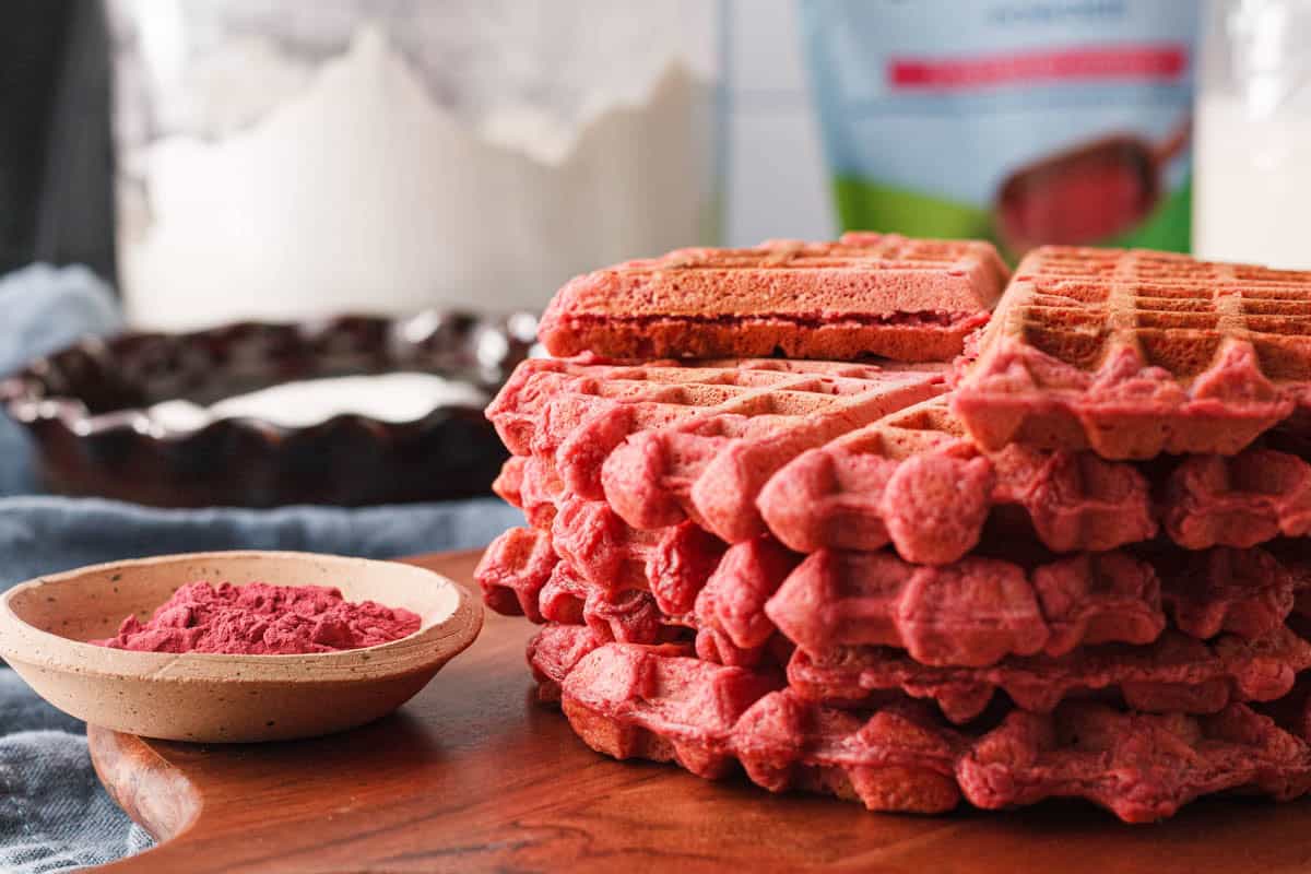 side angle of stacked beetroot waffles with a small bowl of beetroot powder to the side