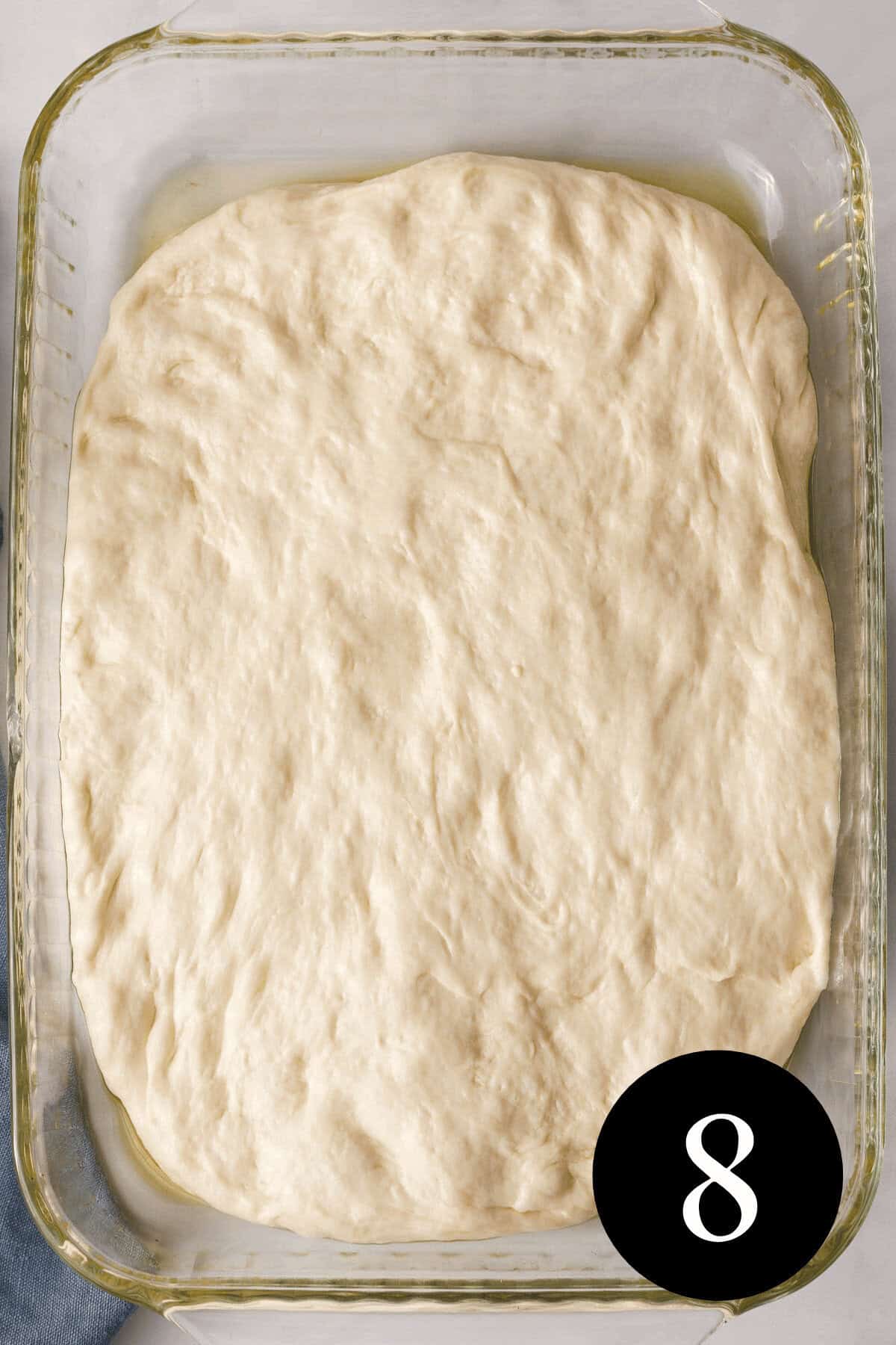overhead image of focaccia dough stretched to edges of baking dish