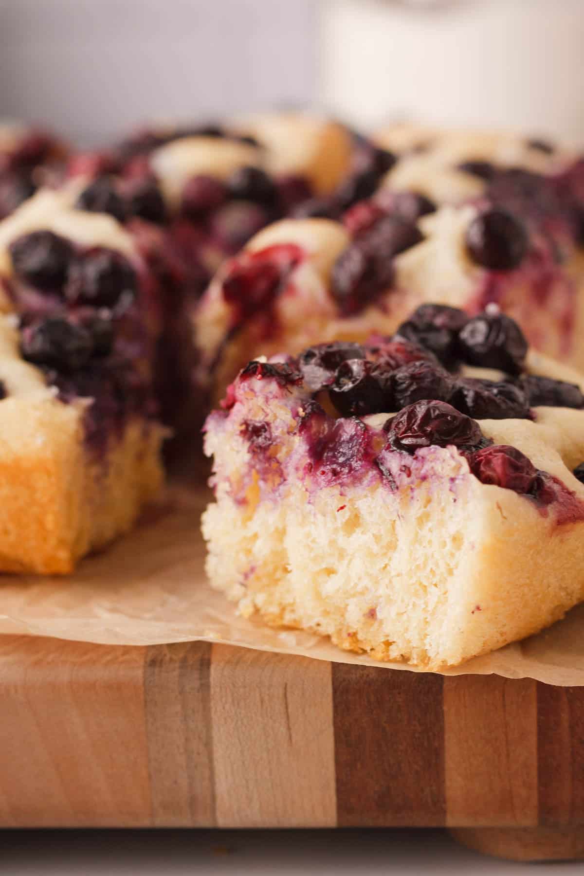 vertical side image of blueberry focaccia slice pulled aside from the rest of the bread to show interior texture