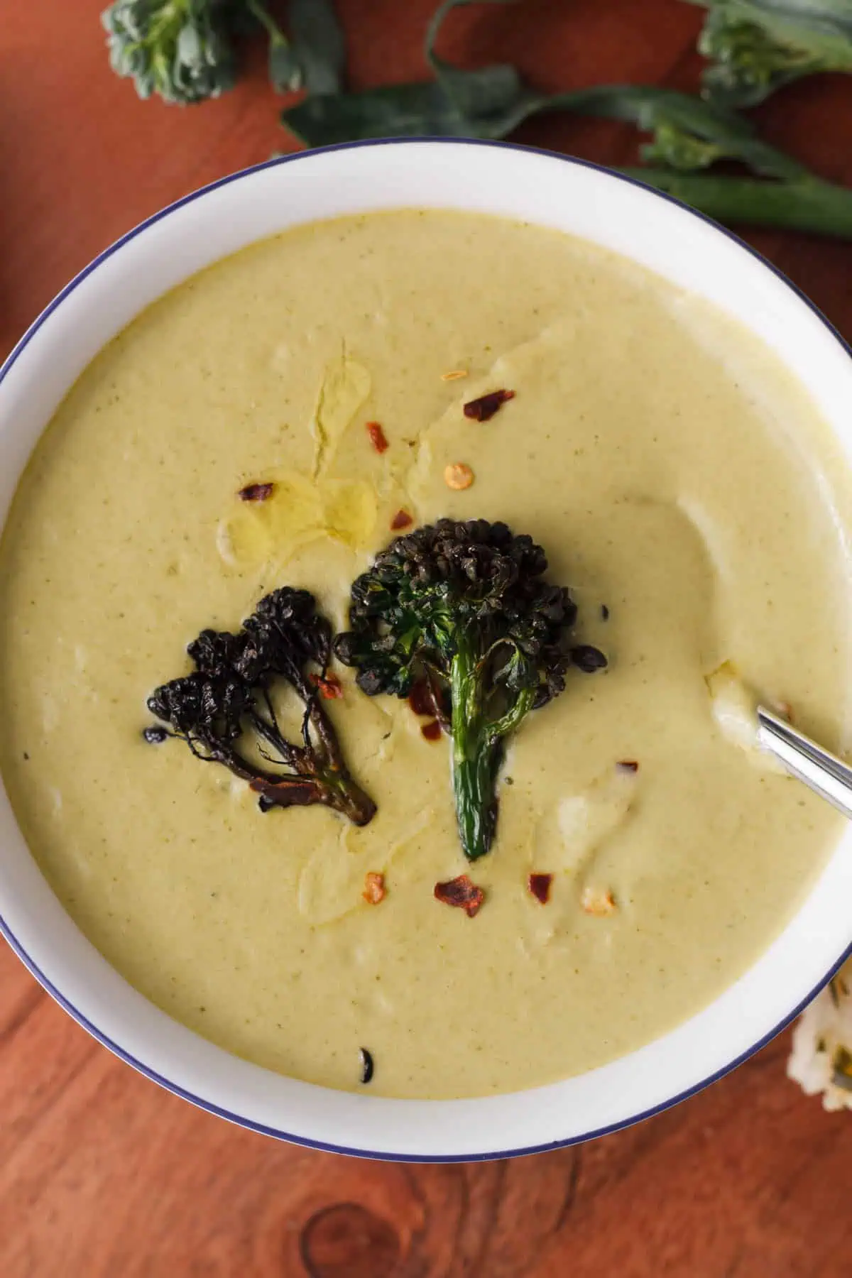closeup overhead image of cream of broccolini soup topped with broccolini croutons and added seasonings for serving