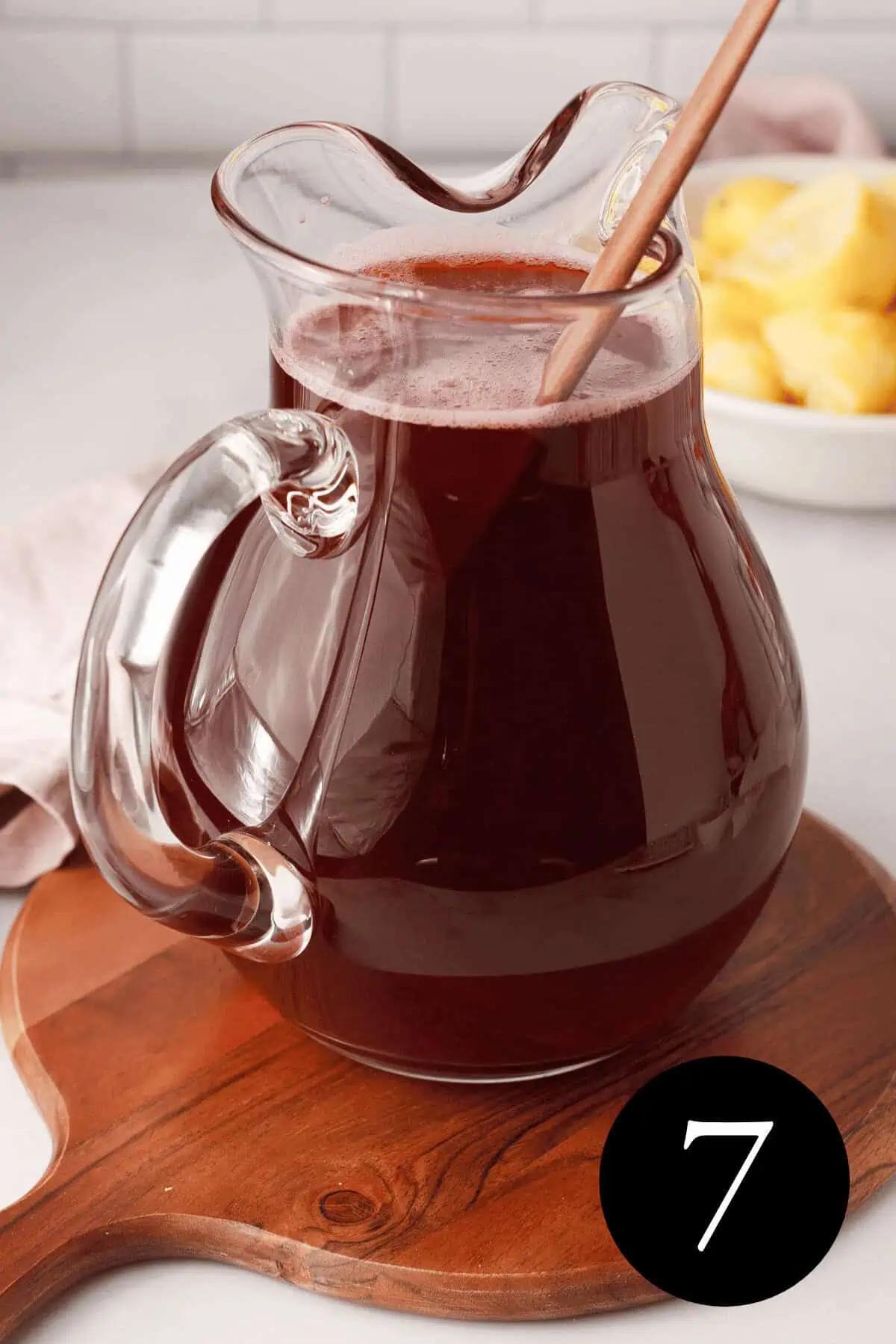 glass pitcher filled with hibiscus lemonade and stir stick resting inside the pitcher