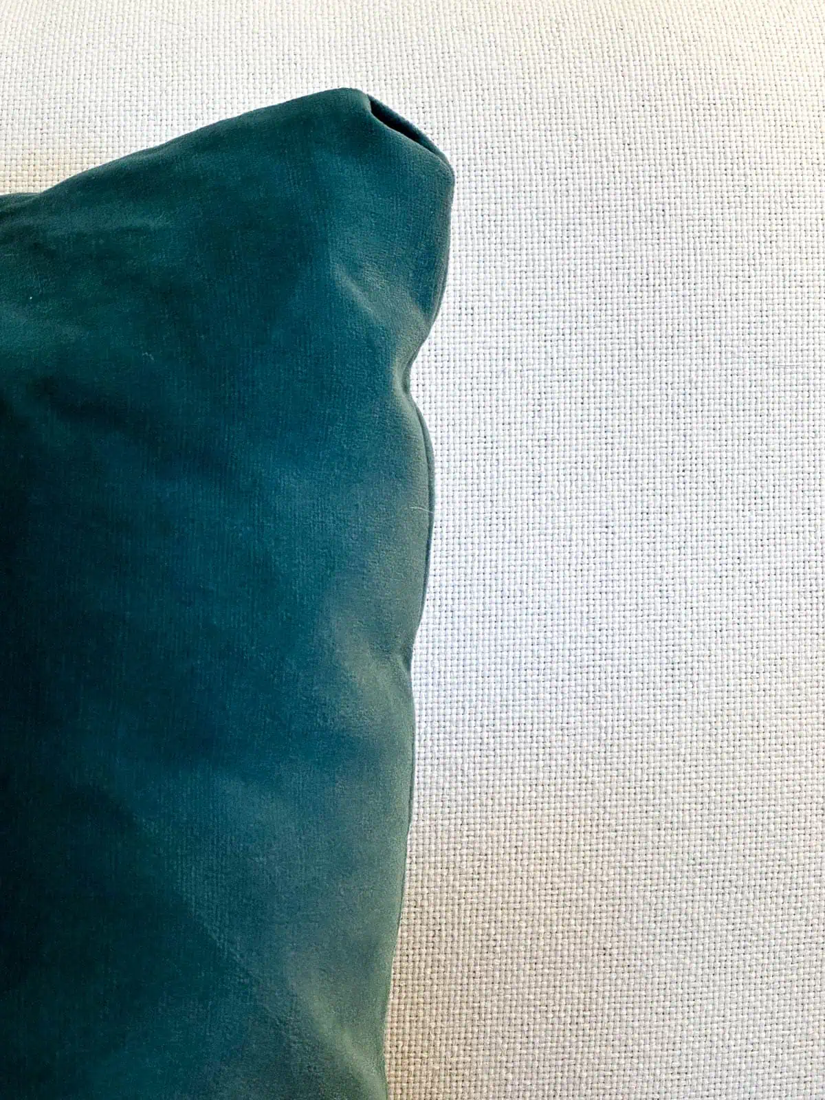 closeup of green pillow with white couch cushion in background to show difference between fabrics
