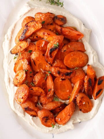 square overhead image of roasted carrots on layer of vegan whipped feta ready for serving