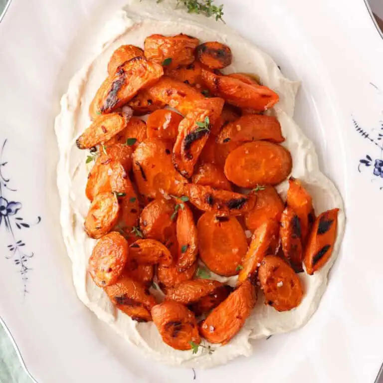 square overhead image of roasted carrots on layer of vegan whipped feta ready for serving