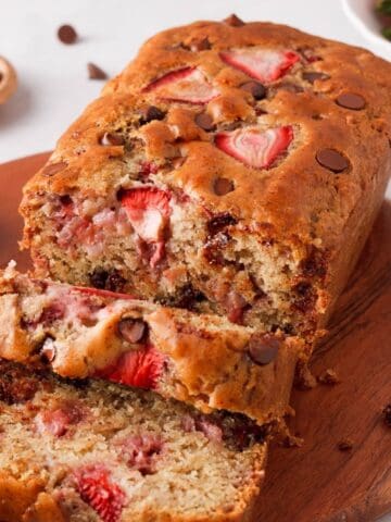 angled image of strawberry chocolate chip bread with a few slices falling forward to show interior