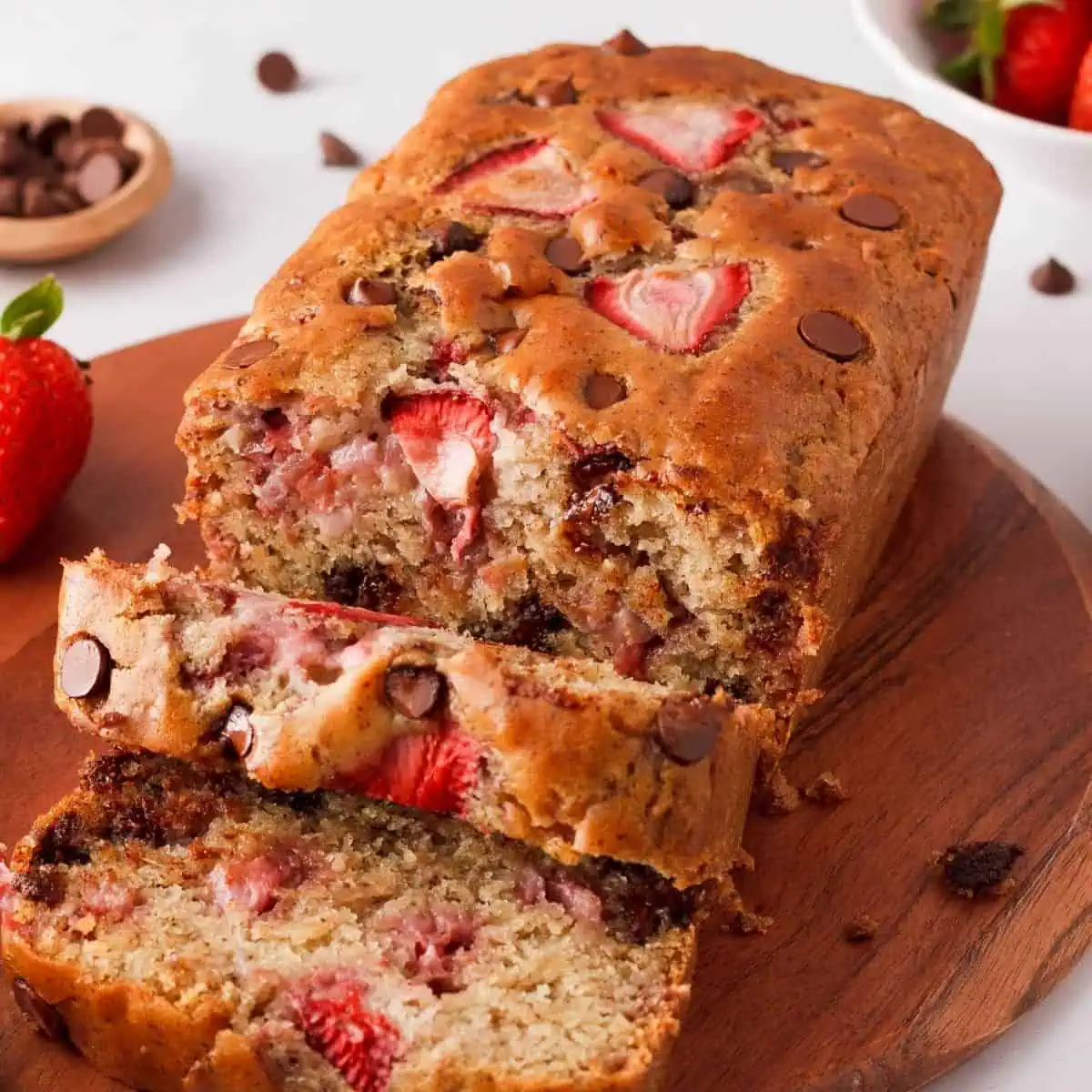 angled image of strawberry chocolate chip bread with a few slices falling forward to show interior
