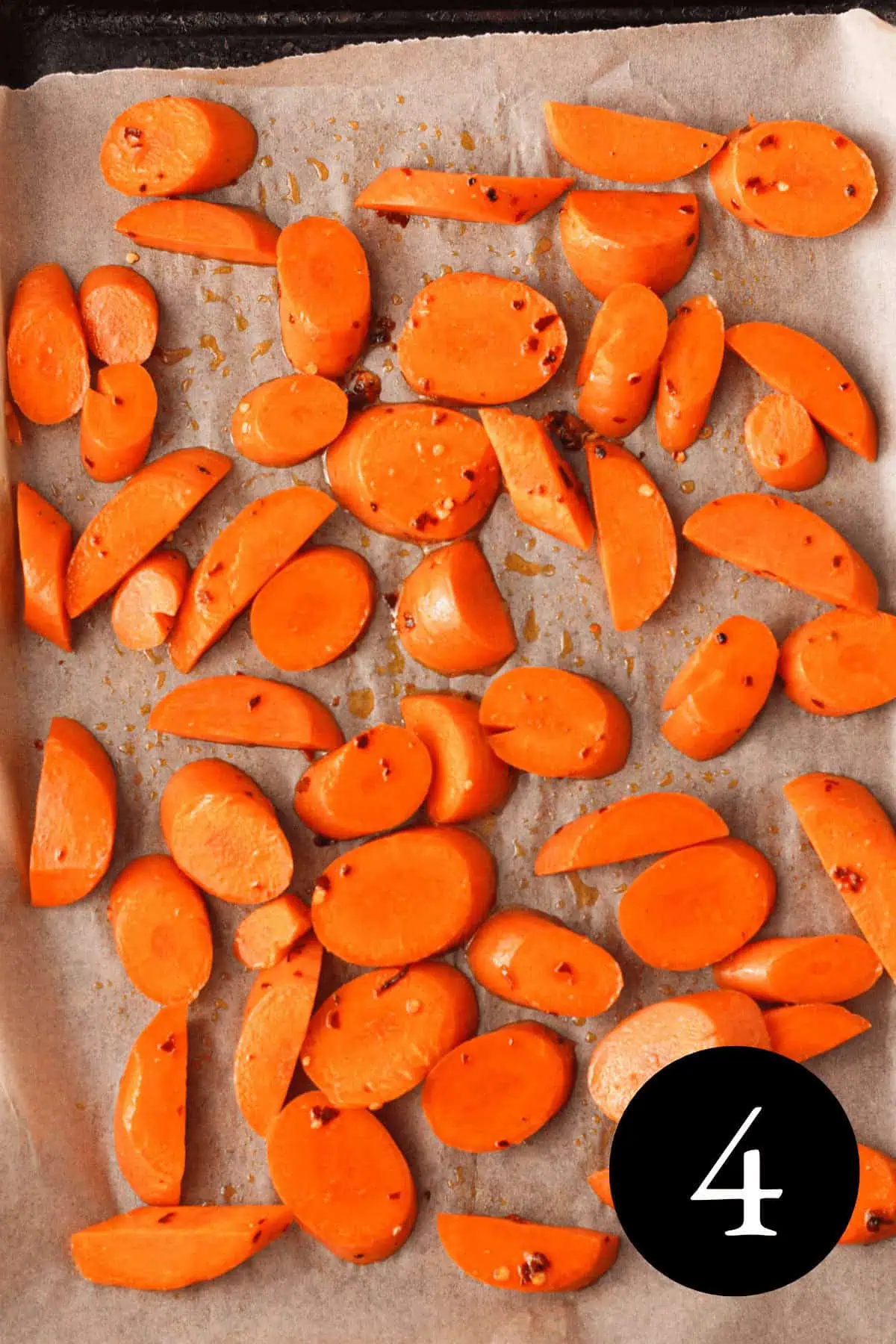 overhead image of sliced carrots on parchment-lined baking sheet