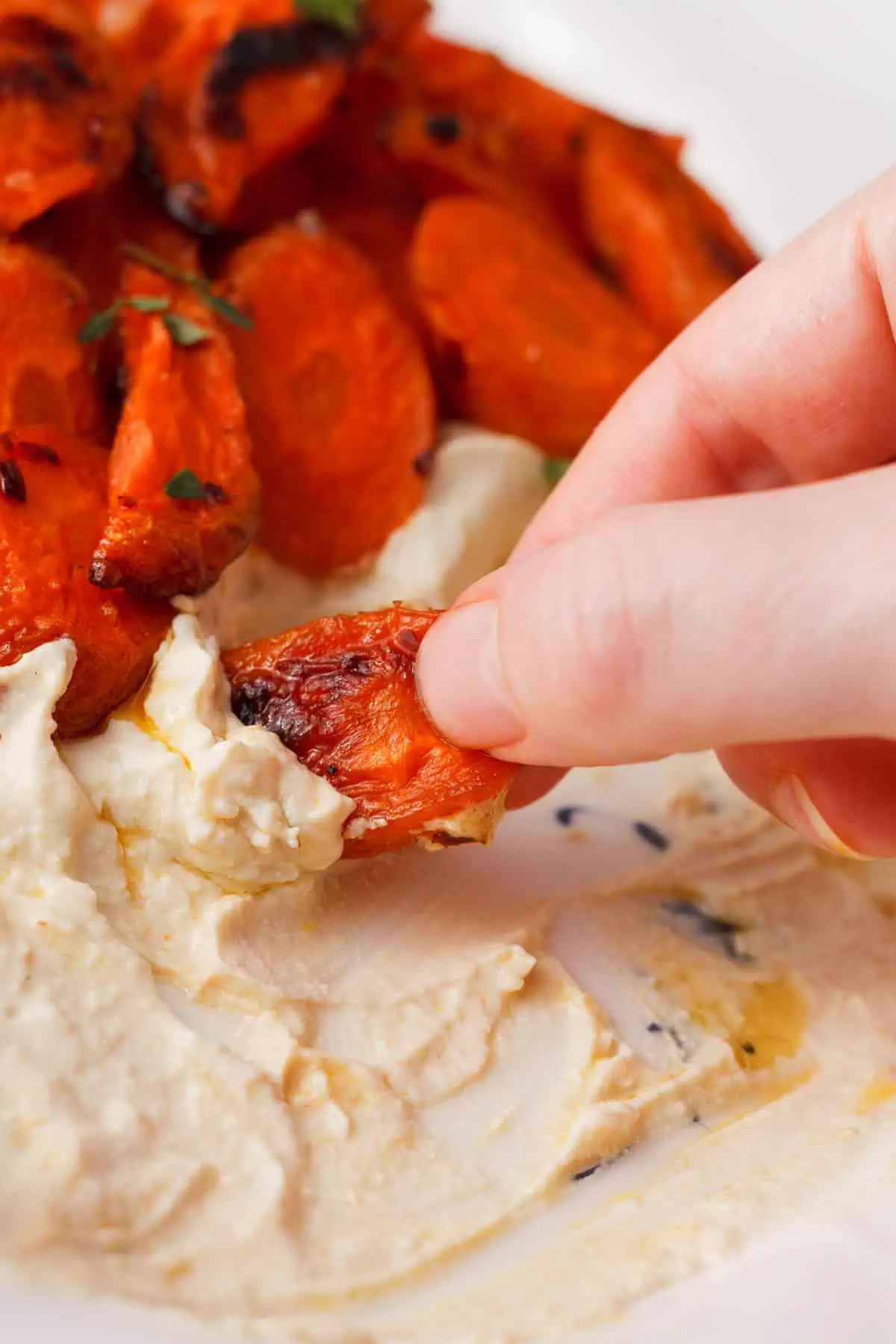 dipping roasted carrot in vegan whipped feta