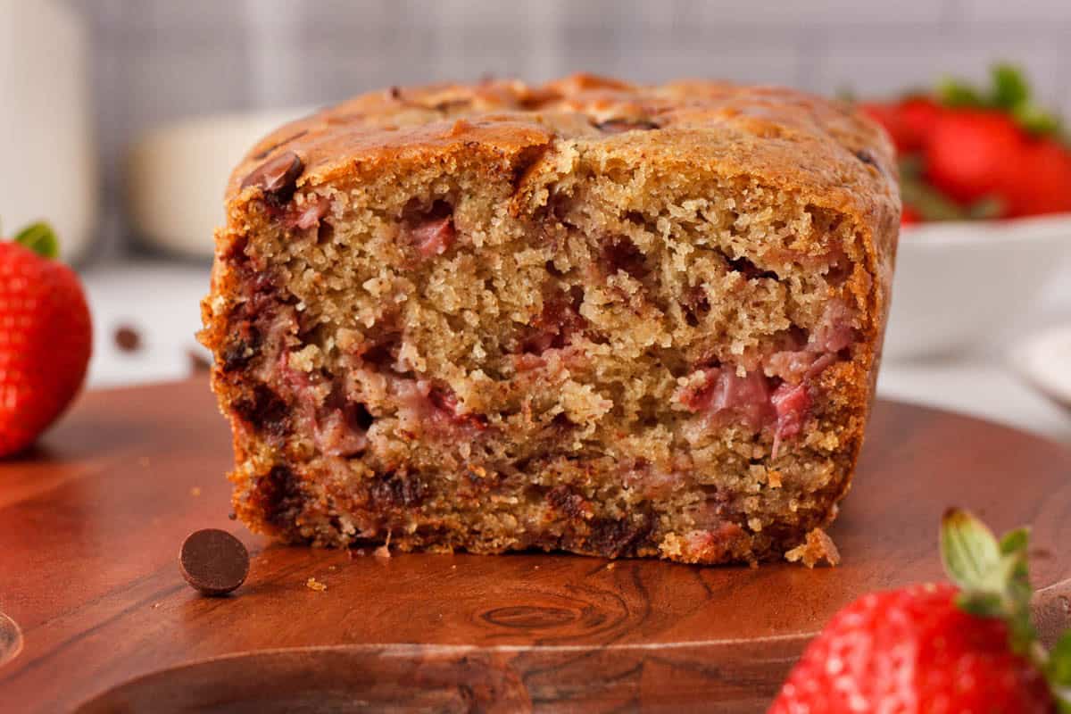 closeup of bread with slice removed to show bits of strawberries, chocolate chips, and bread texture