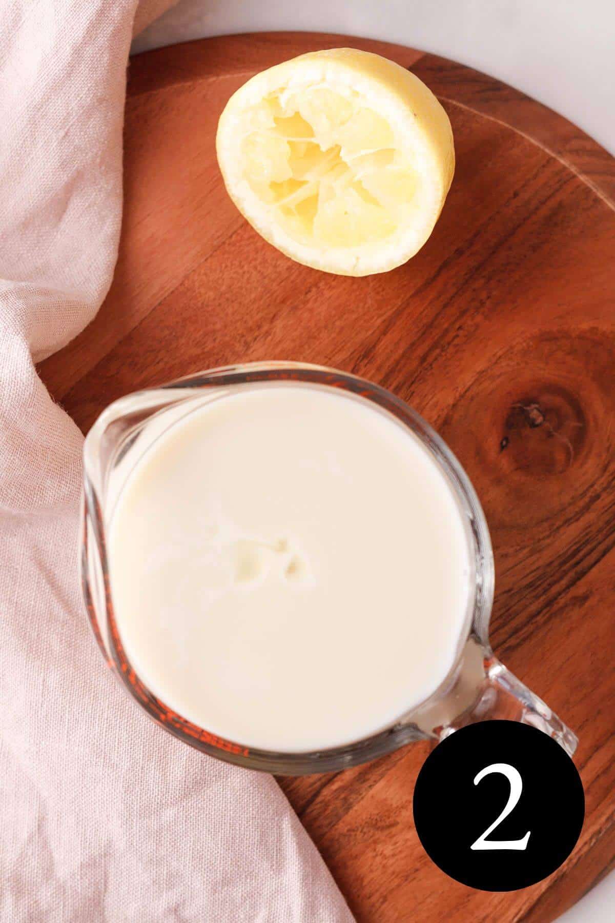 overhead image of plant-based buttermilk in liquid measuring cup with half a lemon next to it