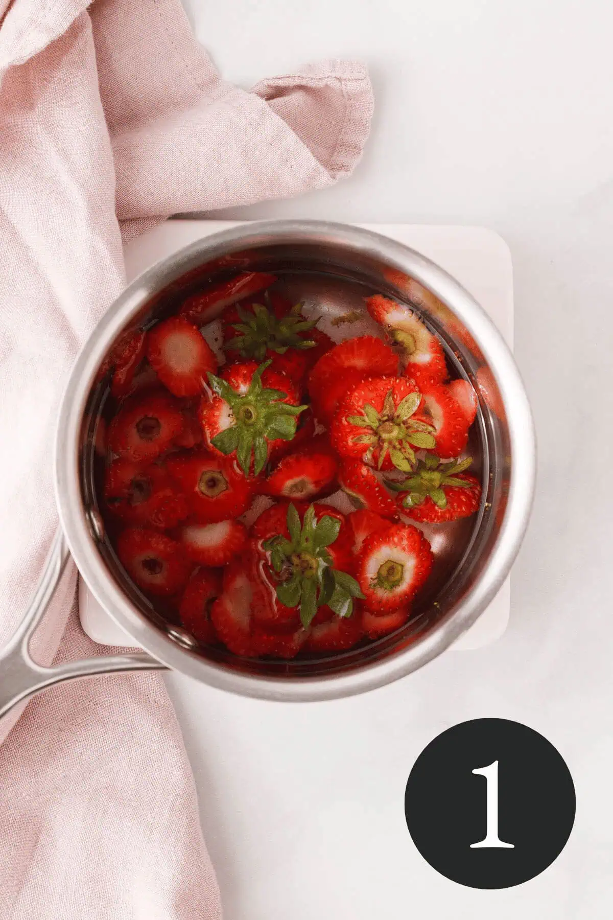 overhead image of strawberry tops and water in saucepan