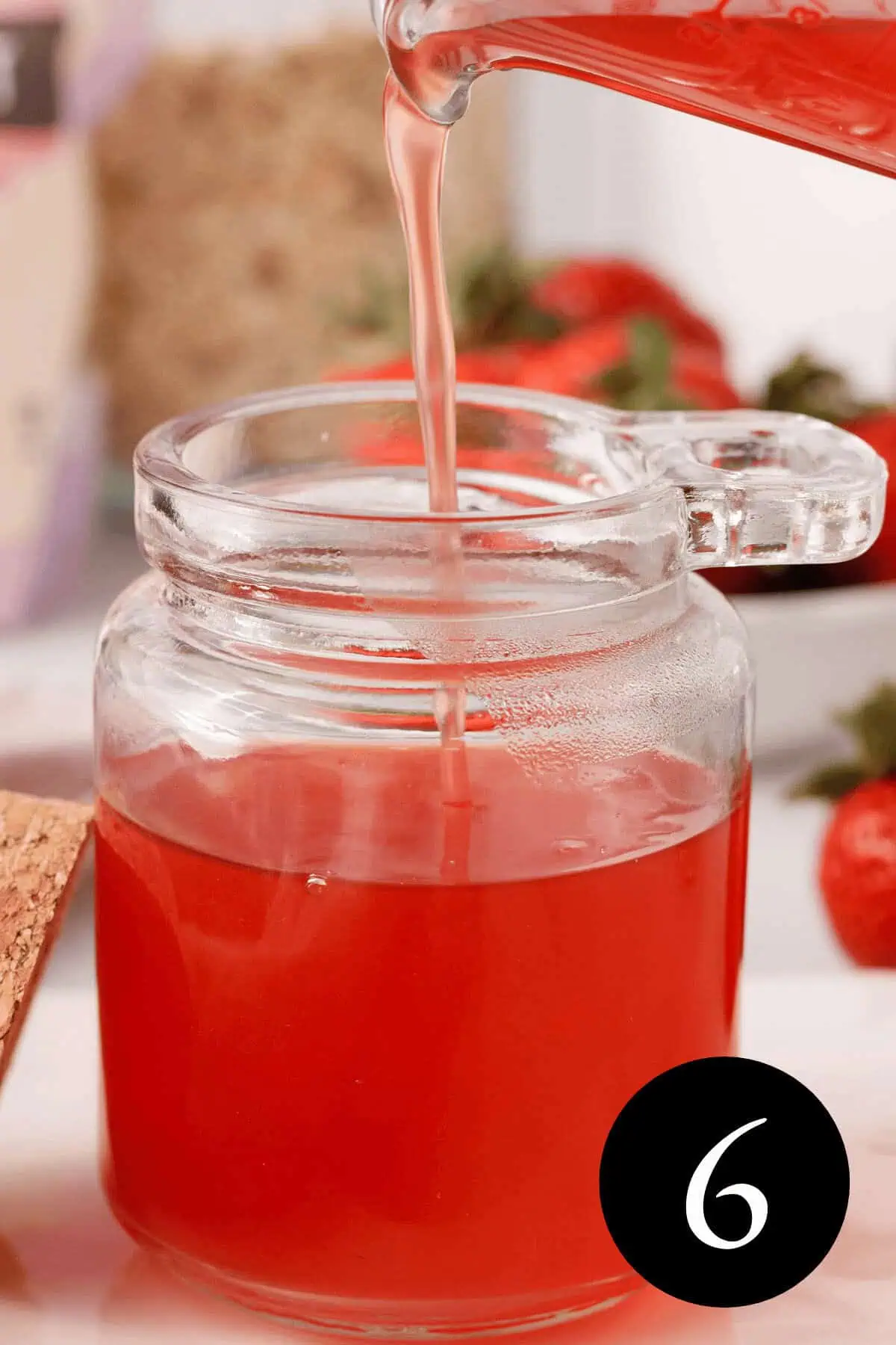 side image of strawberry top syrup pouring into small glass container