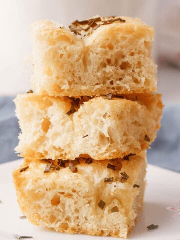 side angle image of chive focaccia pieces stacked on serving plate