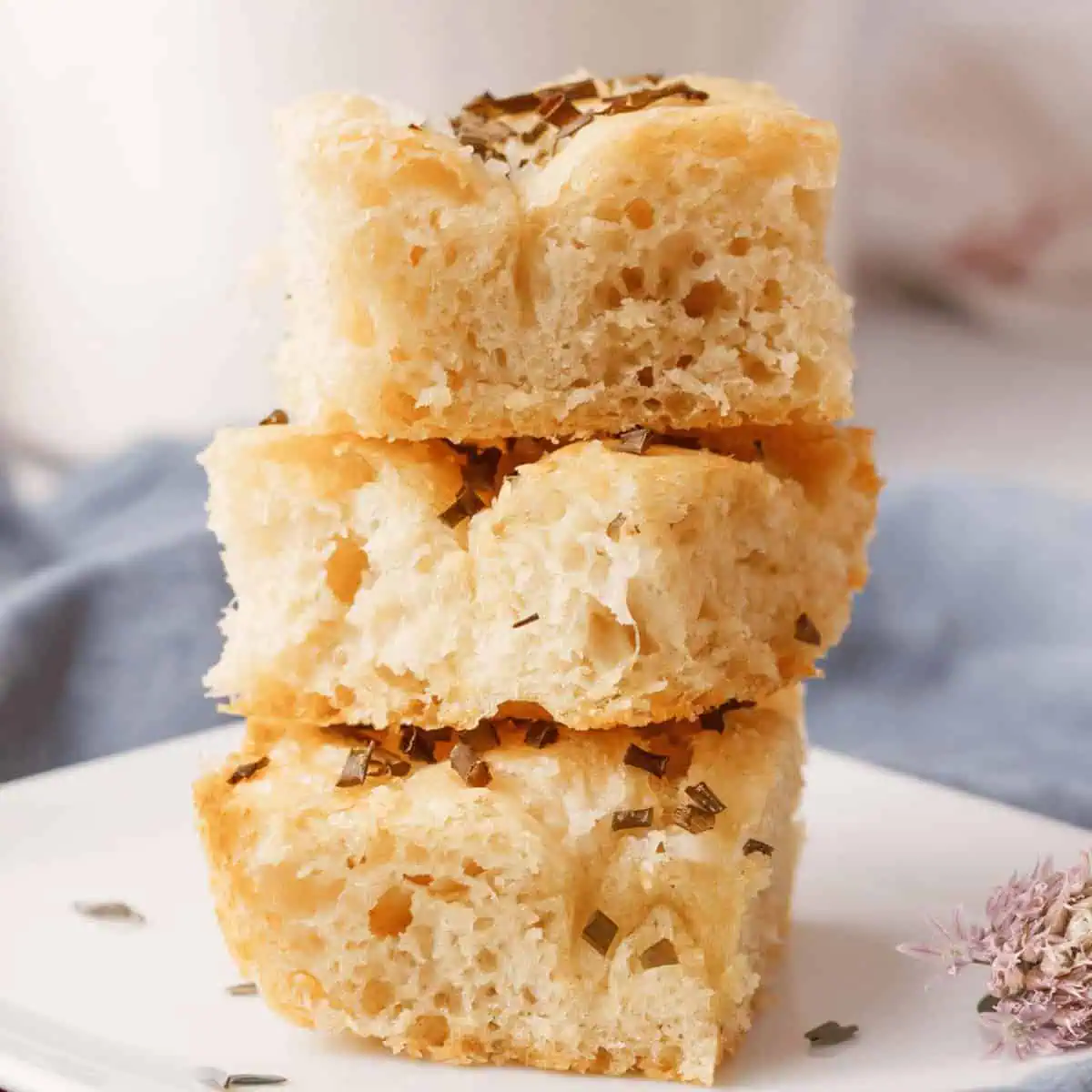 side angle image of chive focaccia pieces stacked on serving plate