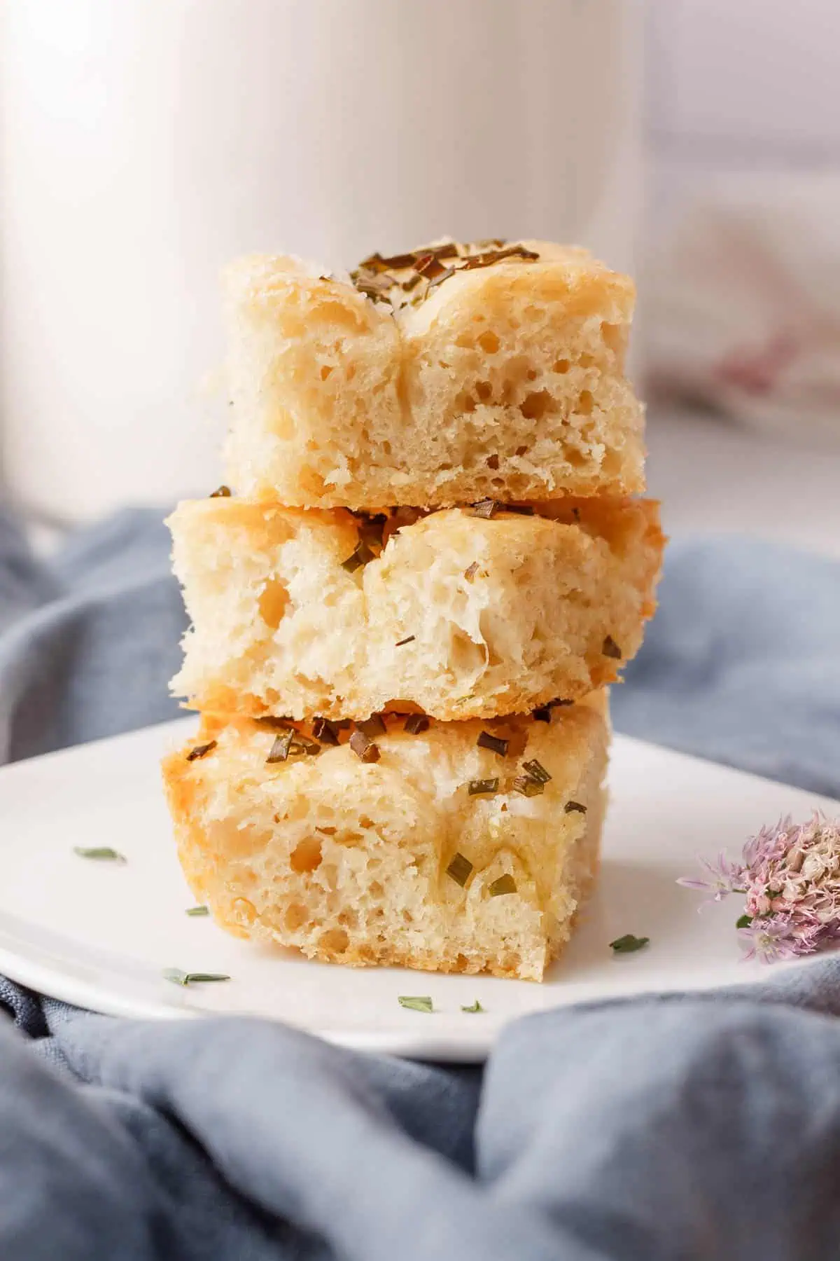 side angle image of three chive focaccia pieces stacked on a serving plate
