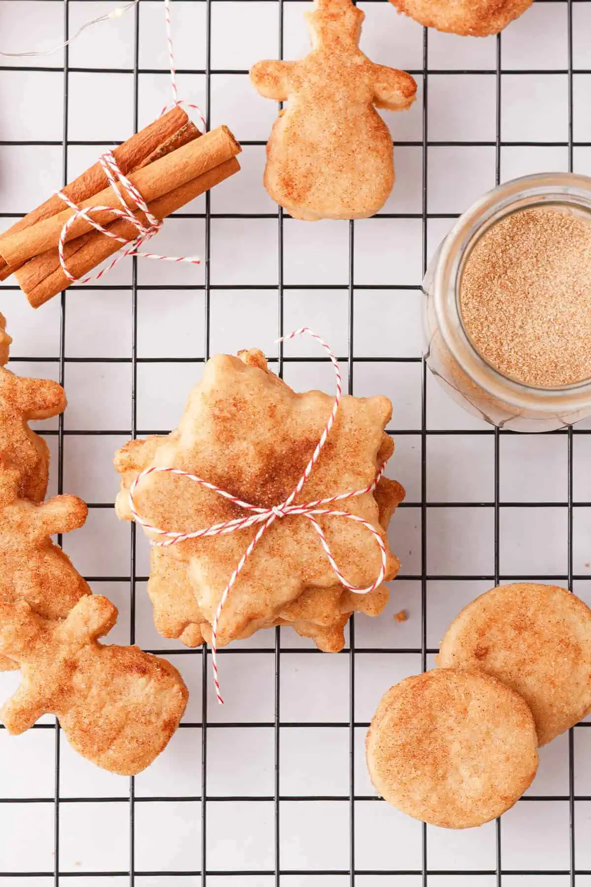 overhead image of baked cinnamon shortbread cookies on cooling rack with accents of cinnamon sticks and jar of cinnamon sugar