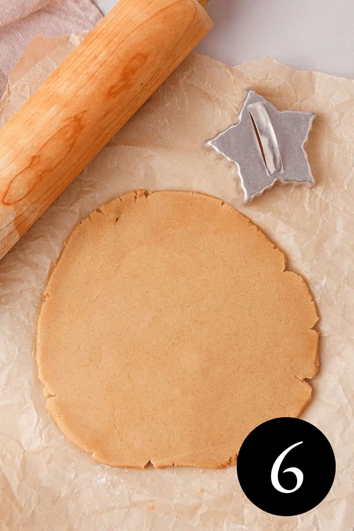 overhead image of cinnamon shortbread dough rolled out on parchment paper with rolling pin and star-shaped cookie cutter resting next to it