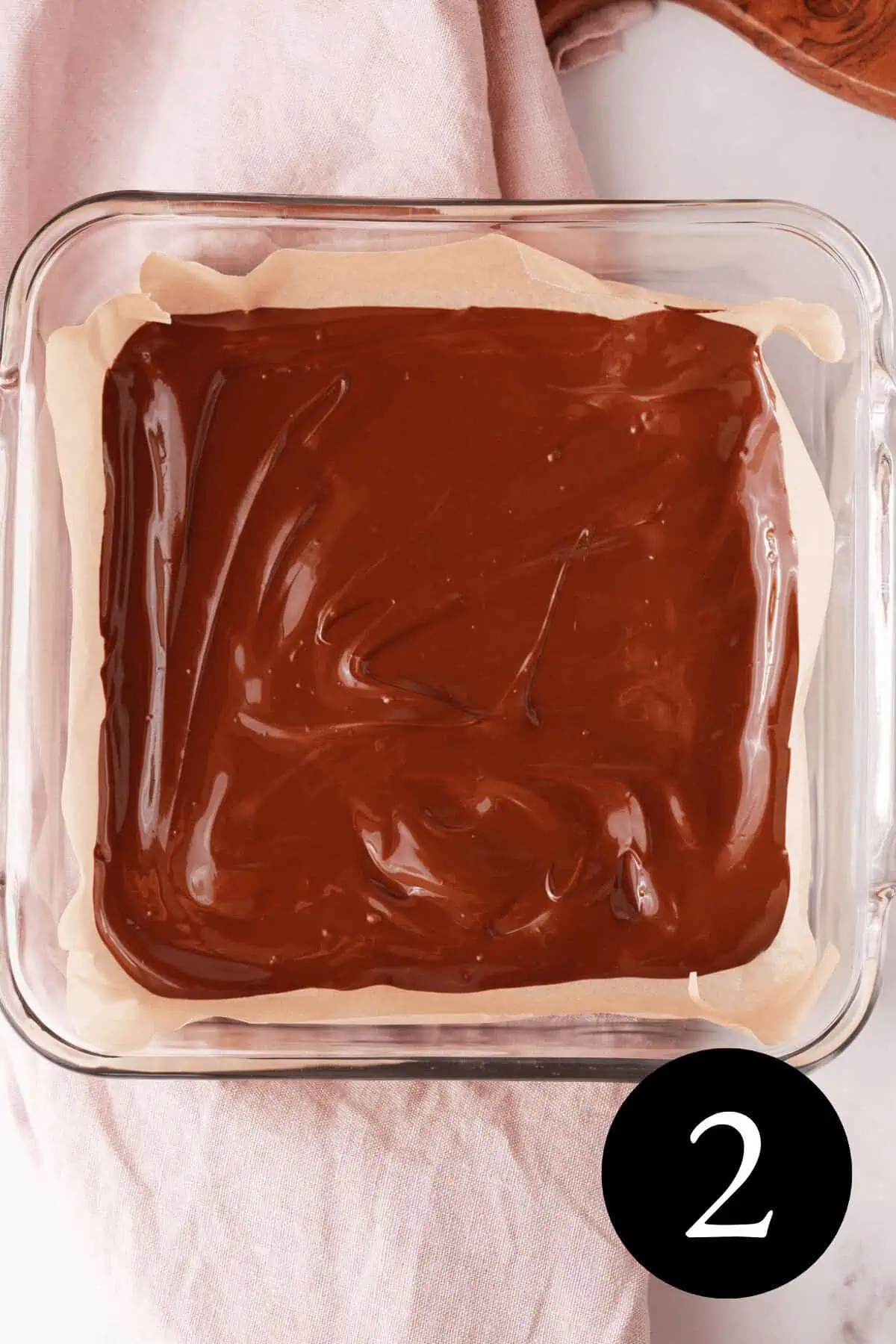 overhead image of melted chocolate in glass baking dish lined with parchment paper