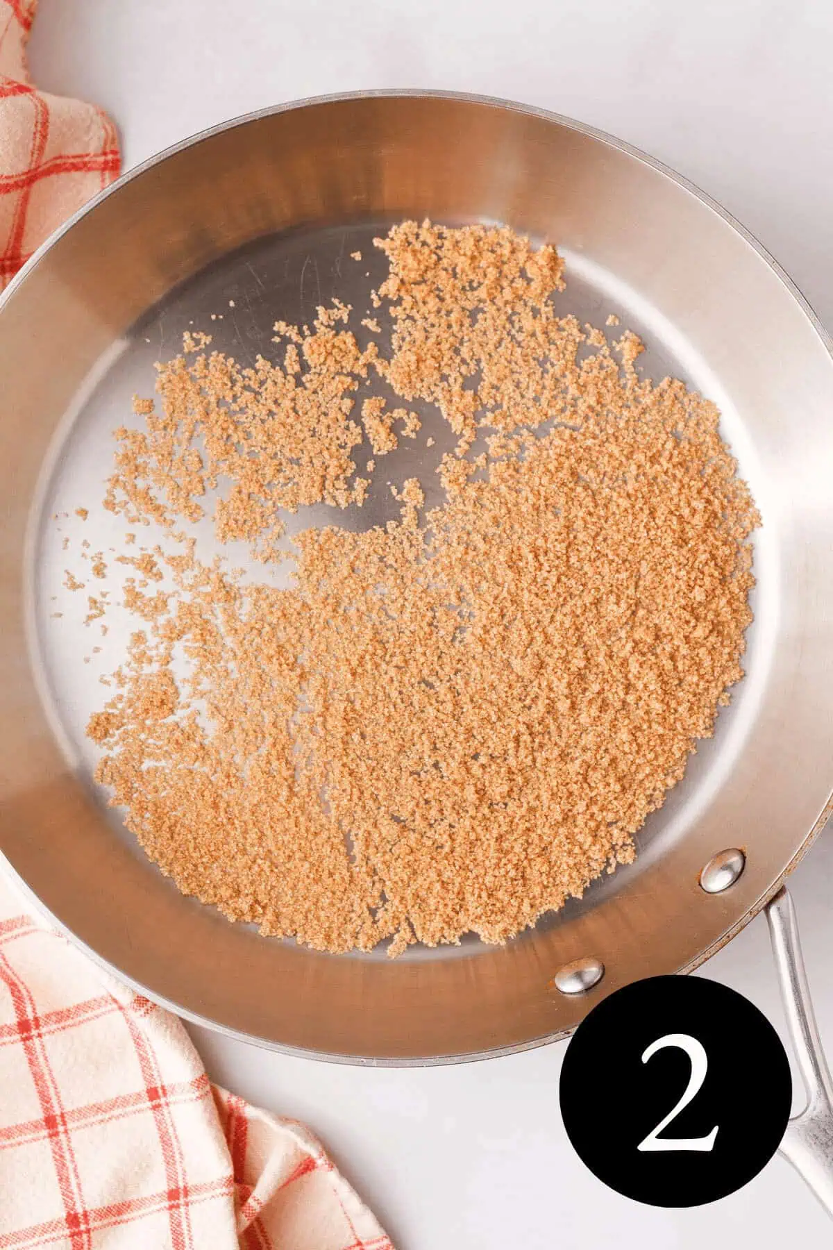 overhead image of light brown sugar granules coating the bottom of skillet before melting and number two in the bottom right corner