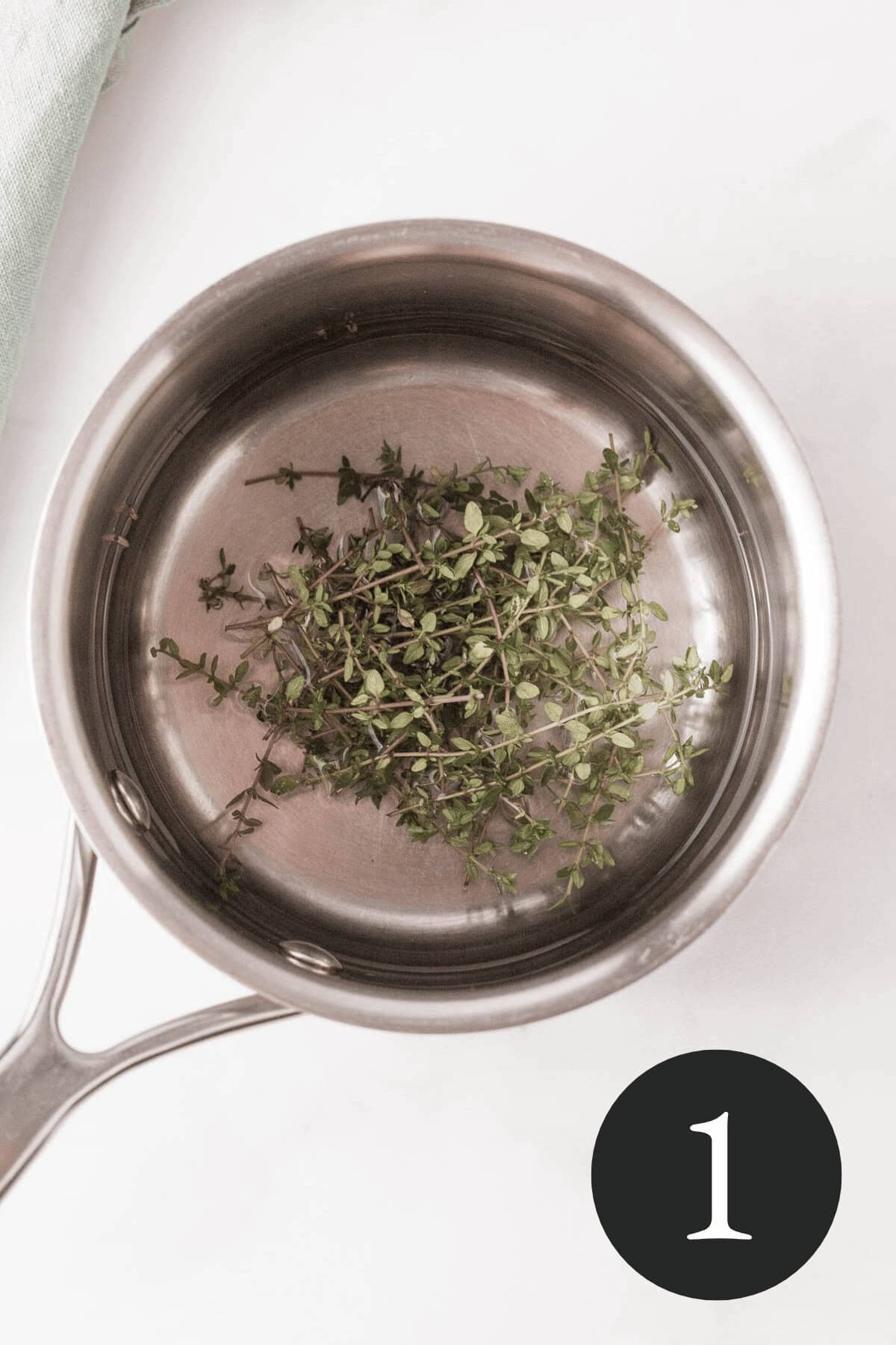 overhead image of fresh thyme sprigs and water in small saucepan